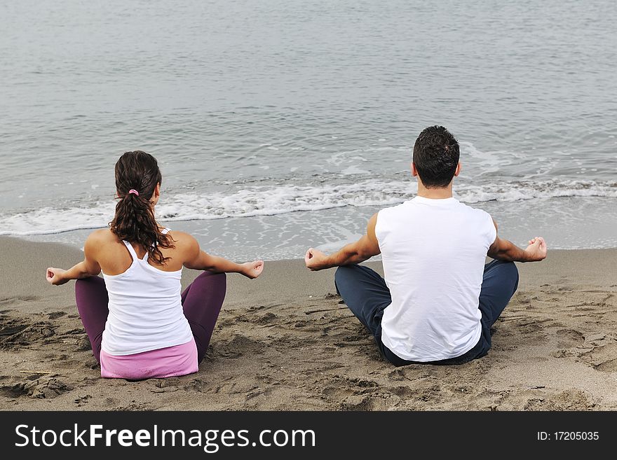 Young couple people meditating yoga in lotus position at early morning on the beach. Young couple people meditating yoga in lotus position at early morning on the beach