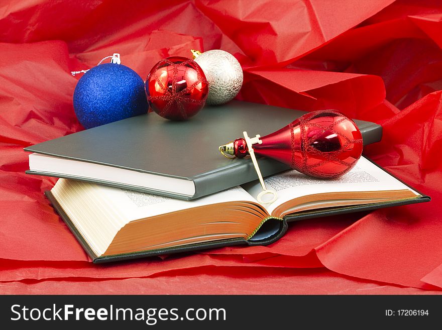 Golden key and open book and closed book on red paper with holiday ornaments reflect the gift that opens knowledge. Golden key and open book and closed book on red paper with holiday ornaments reflect the gift that opens knowledge
