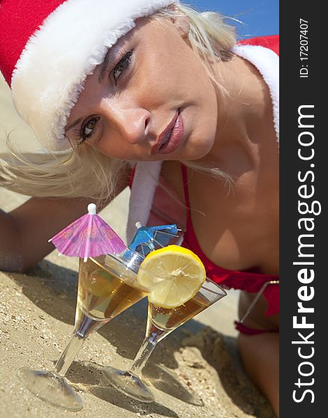 Young women in christmas suit with two martini glasses on the beachfront. Young women in christmas suit with two martini glasses on the beachfront