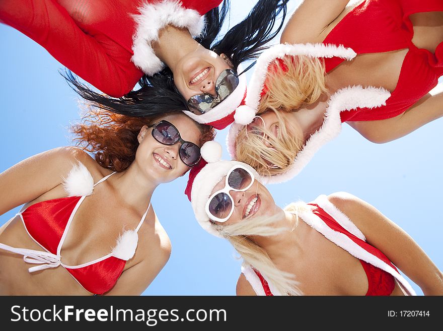 Low angle view of happy girls in christmas suit standing together in a circle against blue sky