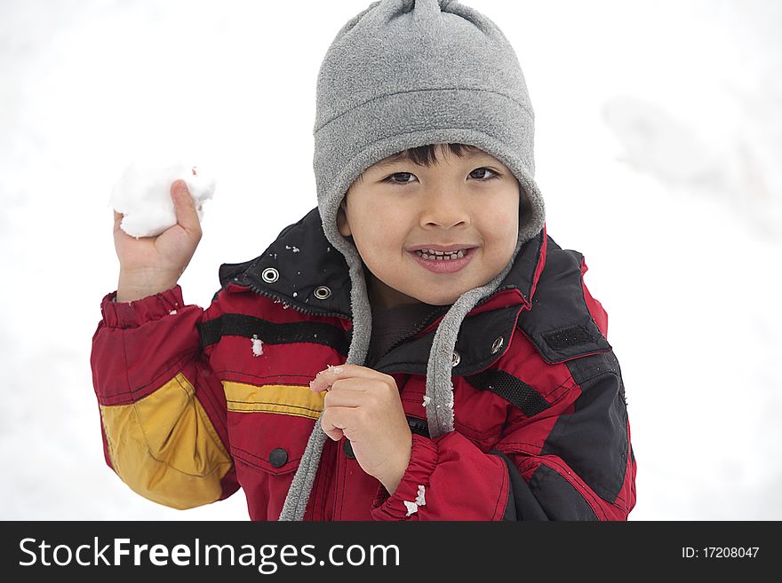 A young boy holds a snowball and looks like he is ready to throw it. A young boy holds a snowball and looks like he is ready to throw it.