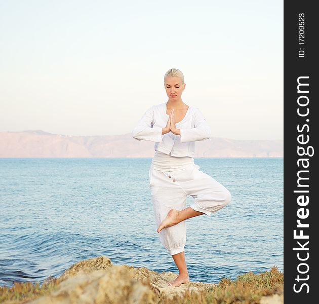 Beautiful young woman doing yoga exercise outdoors