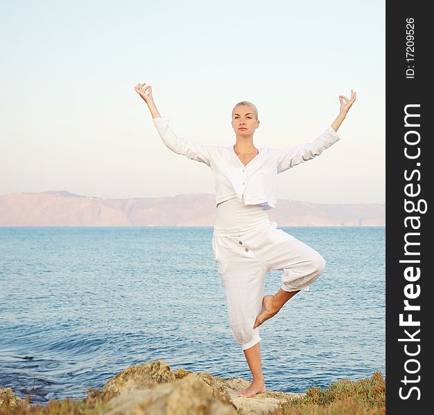 Beautiful young woman doing yoga exercise outdoors