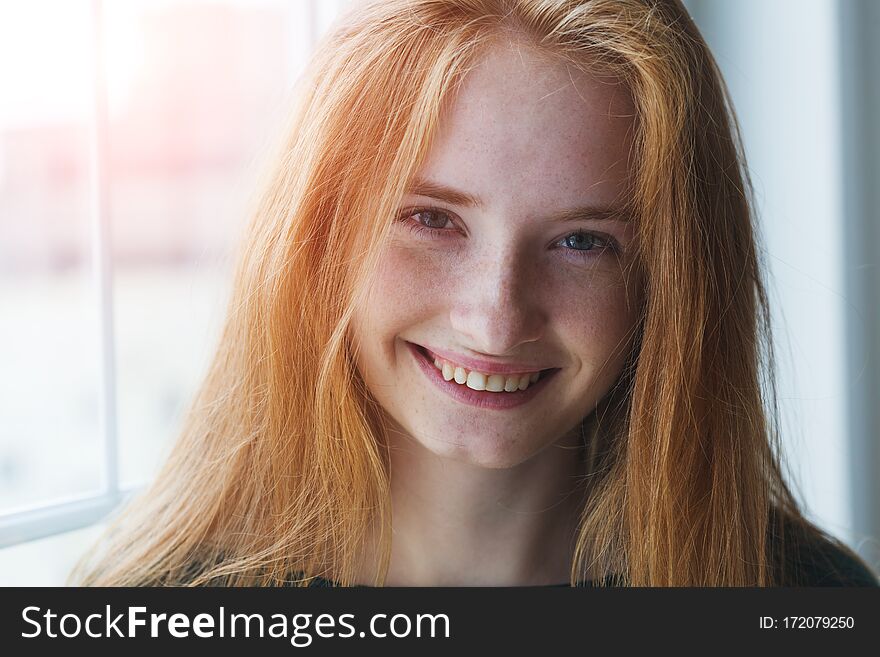 Pretty healthy cheerful joyful red haired young girl looking at camera with charming smile