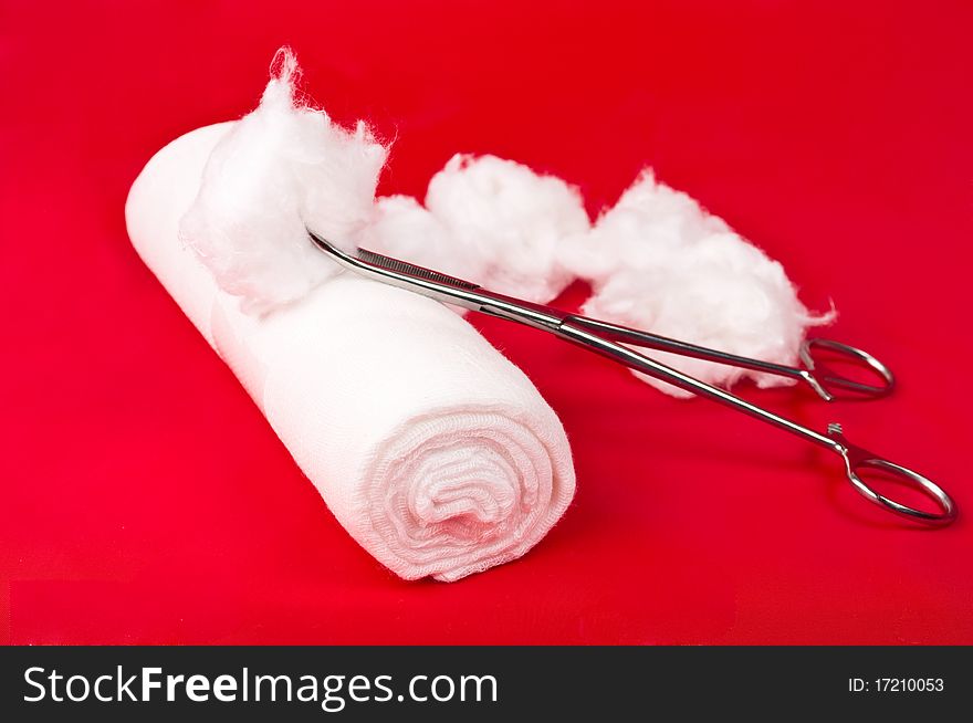 Bandage with a surgical instrument and the wool on a red background