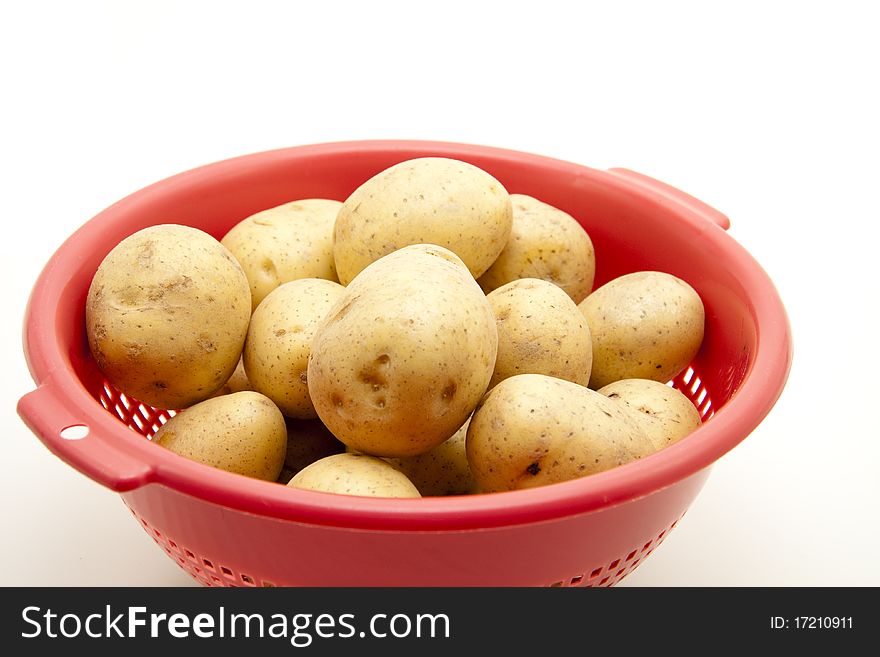 Potatoes in the red kitchen sieve. Potatoes in the red kitchen sieve