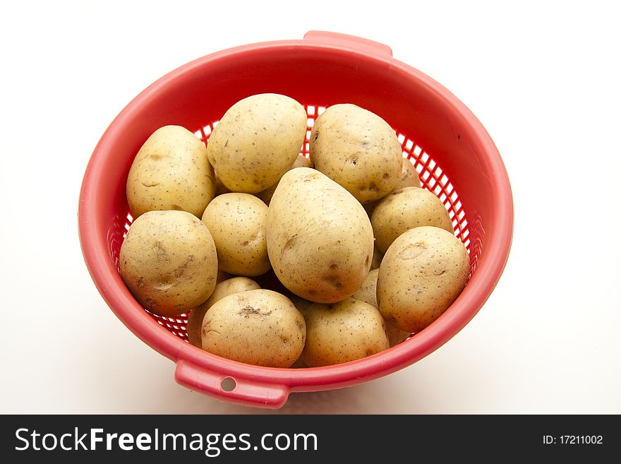 Potatoes in the red kitchen sieve. Potatoes in the red kitchen sieve