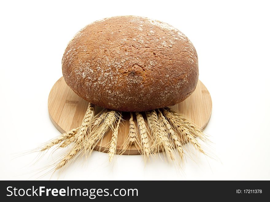 Round bread onto wood plates with wheat ears. Round bread onto wood plates with wheat ears