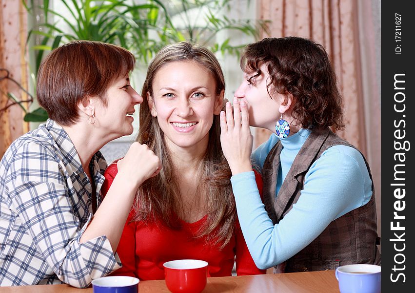 Two women share secrets with a friend at home