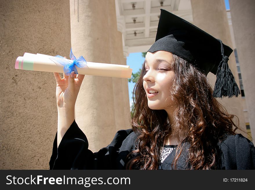 Young student in gown near the university with diploma. Young student in gown near the university with diploma