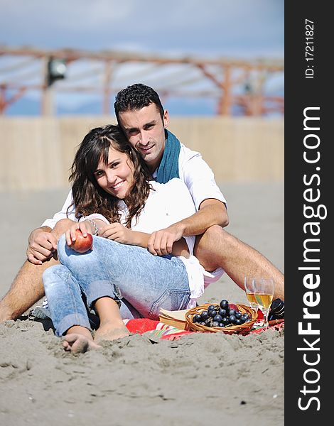 Happy young couple enjoying picnic on the beach and have good time on summer vacations. Happy young couple enjoying picnic on the beach and have good time on summer vacations