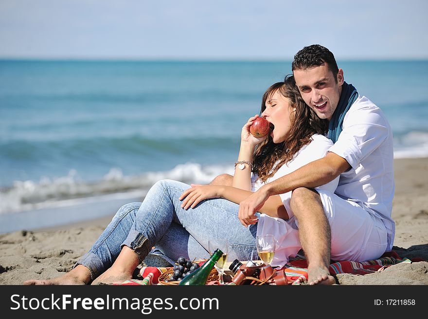 Happy young couple enjoying picnic on the beach and have good time on summer vacations. Happy young couple enjoying picnic on the beach and have good time on summer vacations