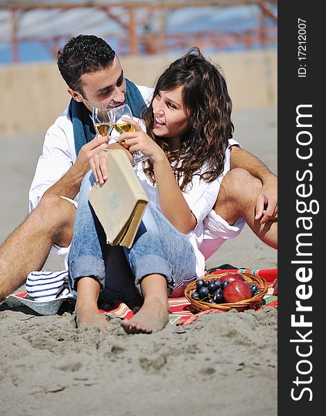 Happy young couple enjoying picnic on the beach and have good time on summer vacations. Happy young couple enjoying picnic on the beach and have good time on summer vacations