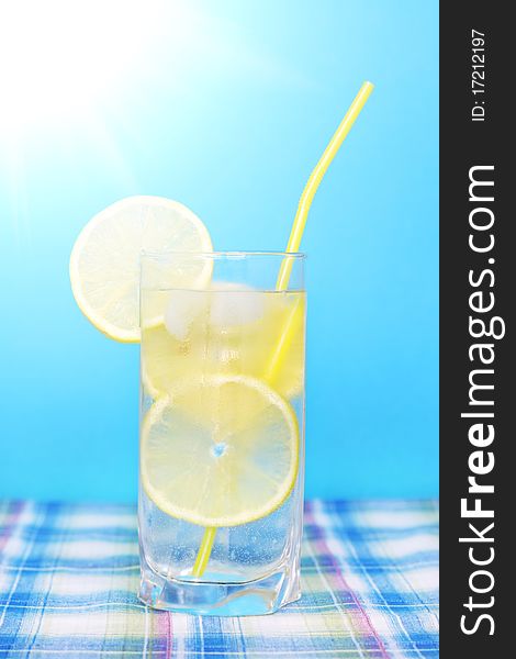 Glass of water with lemon on a blue background