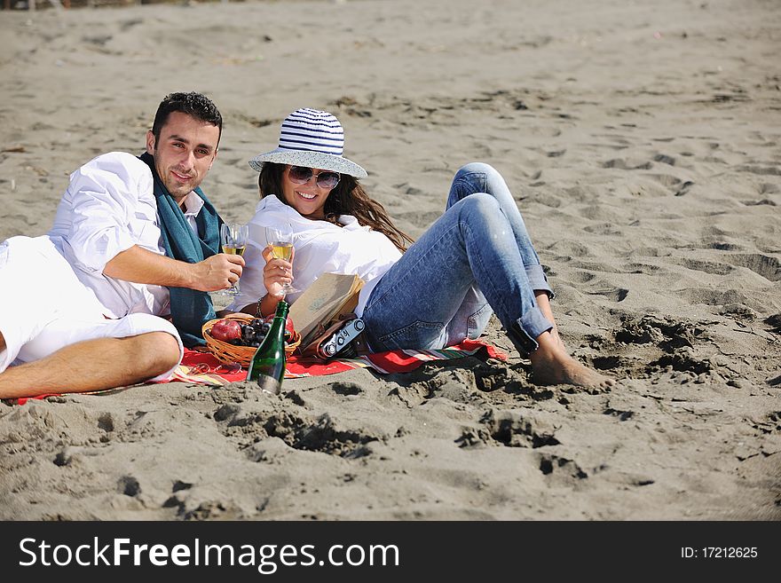 Happy young couple enjoying picnic on the beach and have good time on summer vacations. Happy young couple enjoying picnic on the beach and have good time on summer vacations