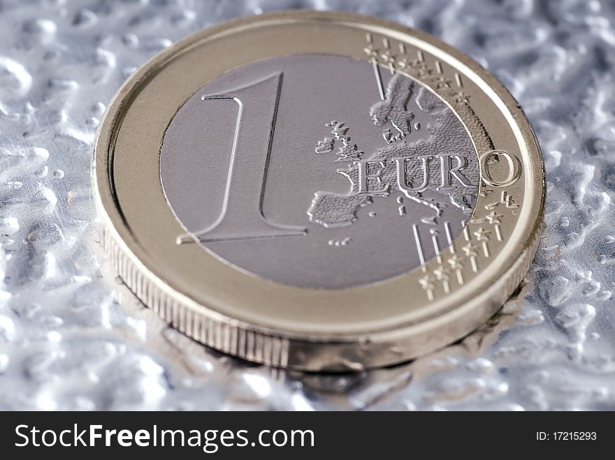 A one euro coin on a flat metal. A one euro coin on a flat metal