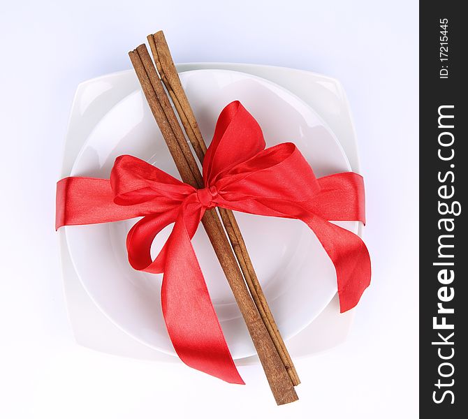 Plate with christmas decoration with cinnamon sticks and ribbon on white background. Plate with christmas decoration with cinnamon sticks and ribbon on white background