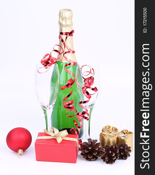 Christmas and New Year's setting - a bottle of champagne, glasses, candles, a gift, and cones on white background