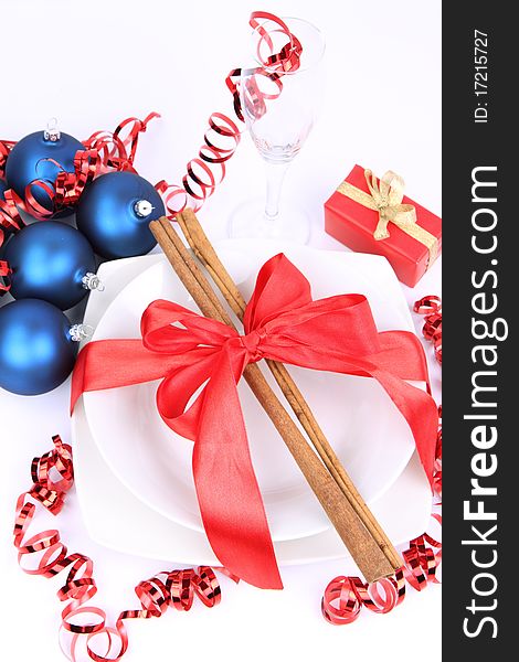 Christmas or New Year's setting - a plate decorated with cinnamon sticks and ribbon, a glass, christmas balls, candles, gift and cones