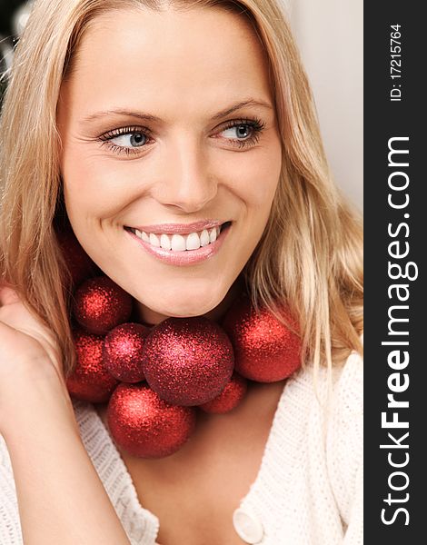 Beautiful blond woman smiling with some christmas balls around her neck. Beautiful blond woman smiling with some christmas balls around her neck