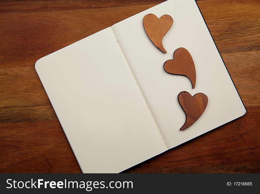 Blank Notebook With Three Hearts On The Wooden Background. Blank Notebook With Three Hearts On The Wooden Background