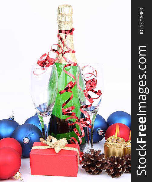 Christmas and New Year's setting - a bottle of champagne, glasses, candles, a gift, and cones on white background