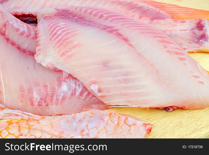 Red tilapia on chopping block .