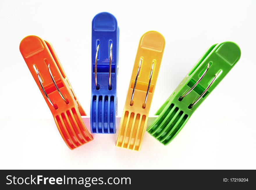 Four colorful clothes pegs over white background