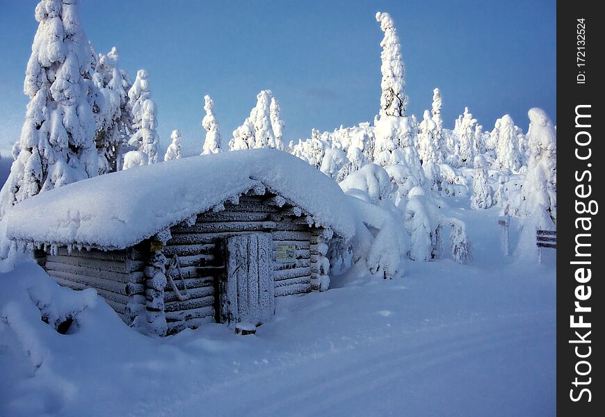 Sunrise in a winter snowy forest in northern Finland. Little hut on the ski track.