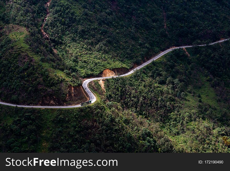 Top view ofcountryside road passing through the green forrest and mountain