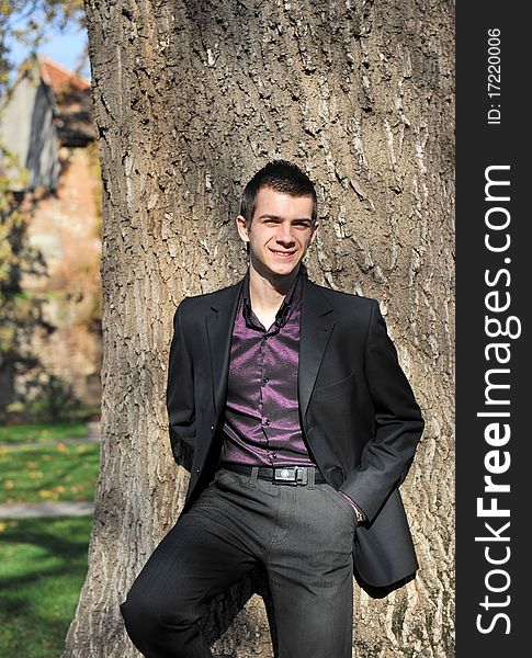 Portrait of happy attractive young man leaning on a tree. Portrait of happy attractive young man leaning on a tree