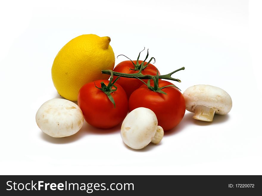 The yellow ripe juicy lemon, red tomato and mushrooms lies on a white background. The yellow ripe juicy lemon, red tomato and mushrooms lies on a white background