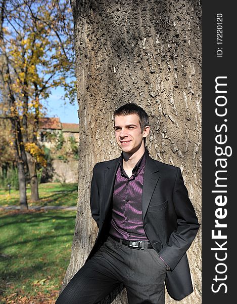 Portrait of happy attractive young man leaning on a tree. Portrait of happy attractive young man leaning on a tree