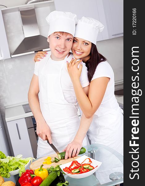 Two happy young cooks making salad in the kitchen. Two happy young cooks making salad in the kitchen