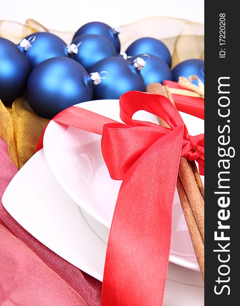 Christmas or New Year's setting - a plate decorated with cinnamon sticks and ribbon, and christmas balls in close up