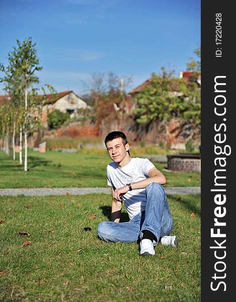 Portrait of happy attractive young man sitting on the grass