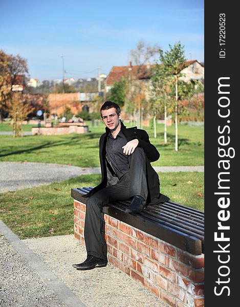 Portrait of happy attractive young man sitting on a bench