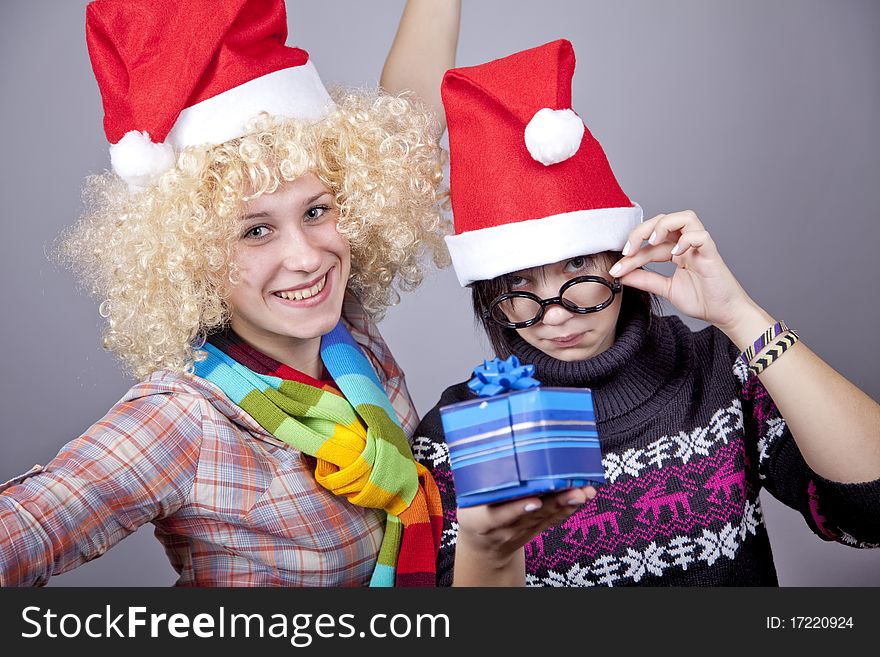 Two beautiful girls with gifts in christmas hats