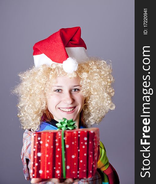 Girl in blonde wig and christmas hat show gift. Studio shot.