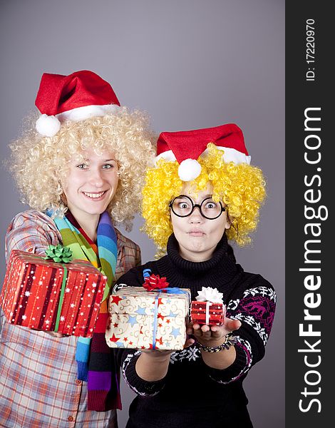 Two beautiful girls with gifts in christmas hats. Studio shot.