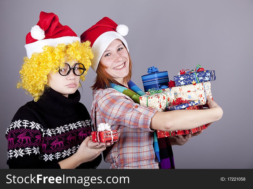 Two funny girls with christmas gifts. Studio shot.