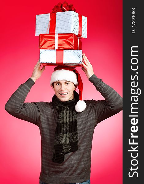 Portrait of a handsome young man in Santa Claus hat holding presents. Christmas. Portrait of a handsome young man in Santa Claus hat holding presents. Christmas.