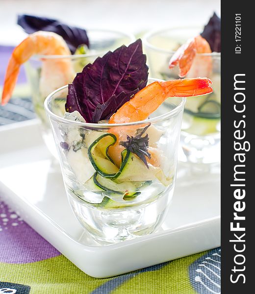 Tasty prawns appetizer with zucchini, cheese and basil in glass