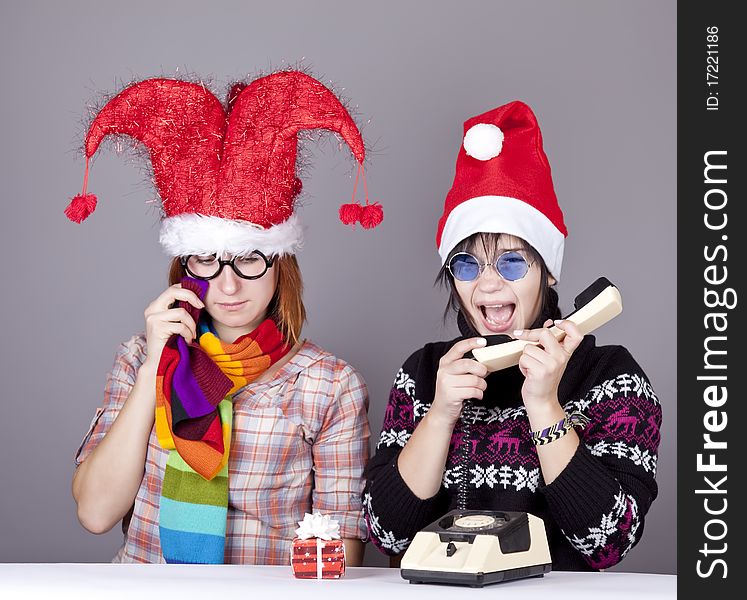 Two girls calling to Santa for better christmas gift. Studio shot.