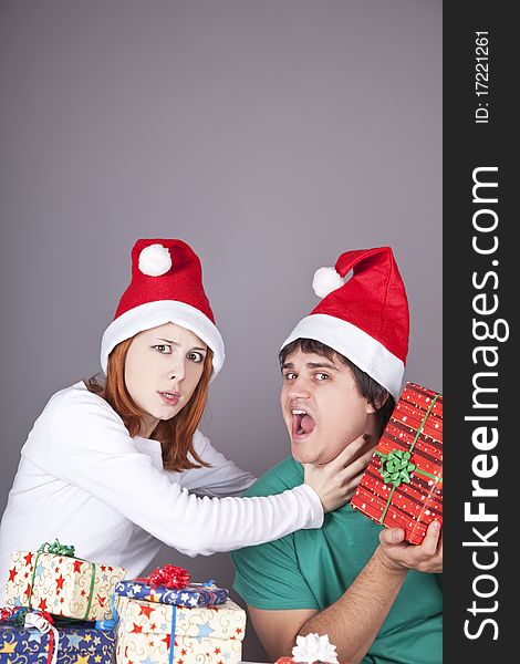 Girl strangling her boyfriend for a christmas gift. Studio shot.