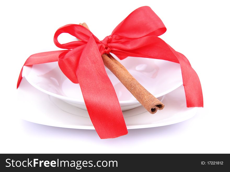 Christmas tableware-a plate decorated with cinnamon sticks and ribbon on white background