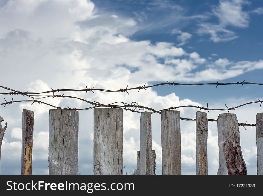 Barbed wire are stretched across top of wooden fence