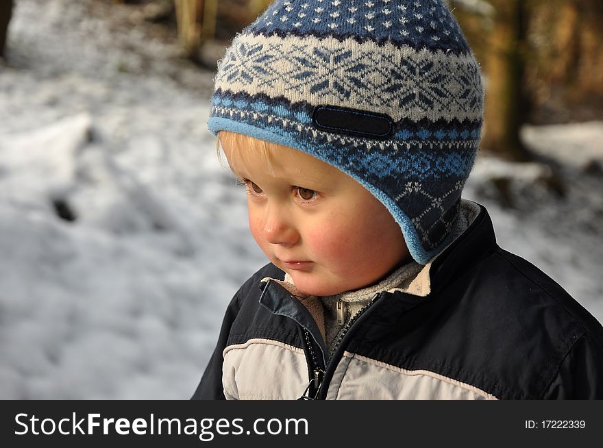 Young boy standing in a snowy forest having nordic style hat on the head. Young boy standing in a snowy forest having nordic style hat on the head