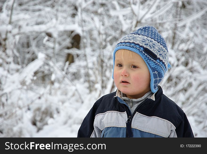 Young boy standing in a snowy scenery having nordic style hat on the head. Young boy standing in a snowy scenery having nordic style hat on the head