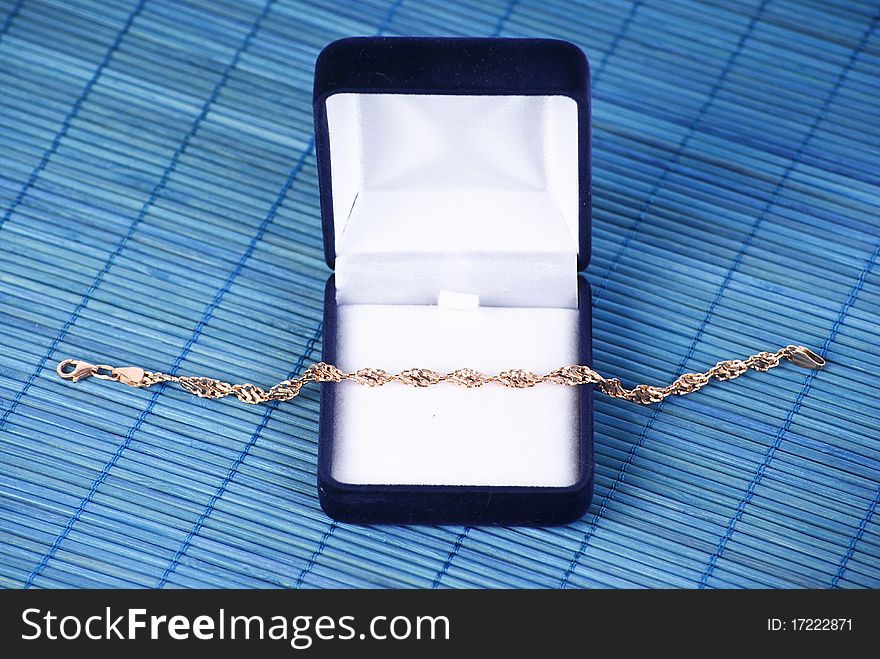 Blue jewerly box with gold bracelet on blue background